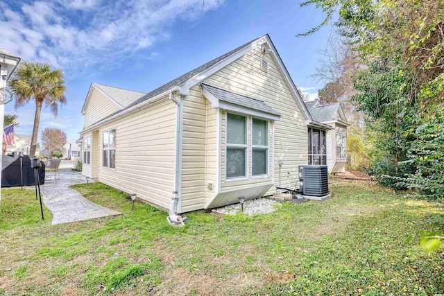 view of side of property with cooling unit, a patio area, and a lawn