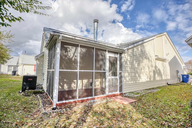 rear view of property featuring a lawn, a sunroom, and central air condition unit