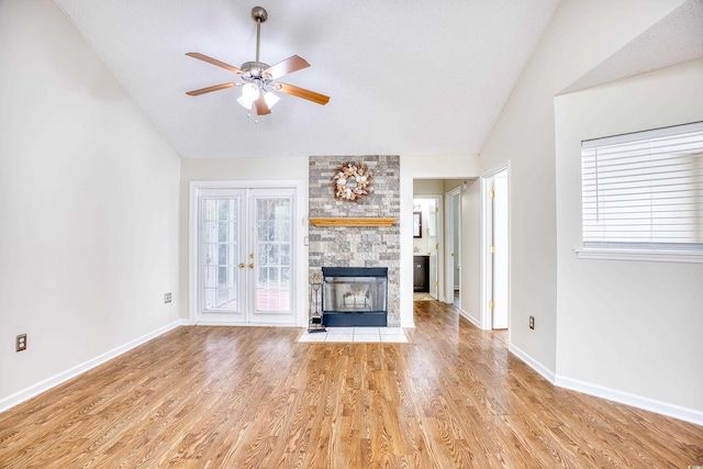 unfurnished living room with lofted ceiling, plenty of natural light, a fireplace, and light hardwood / wood-style flooring