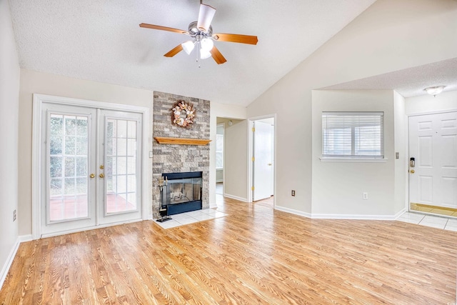 unfurnished living room featuring a healthy amount of sunlight, lofted ceiling, a fireplace, and light wood-type flooring