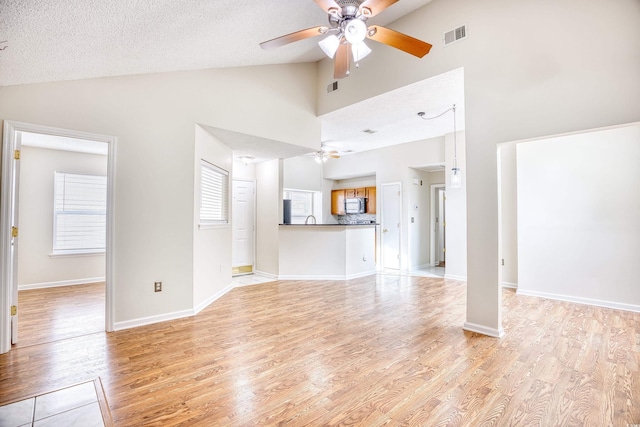 unfurnished living room featuring ceiling fan, lofted ceiling, and light hardwood / wood-style flooring