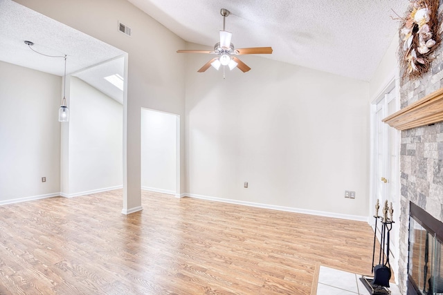 unfurnished living room featuring ceiling fan, a fireplace, vaulted ceiling, and light wood-type flooring