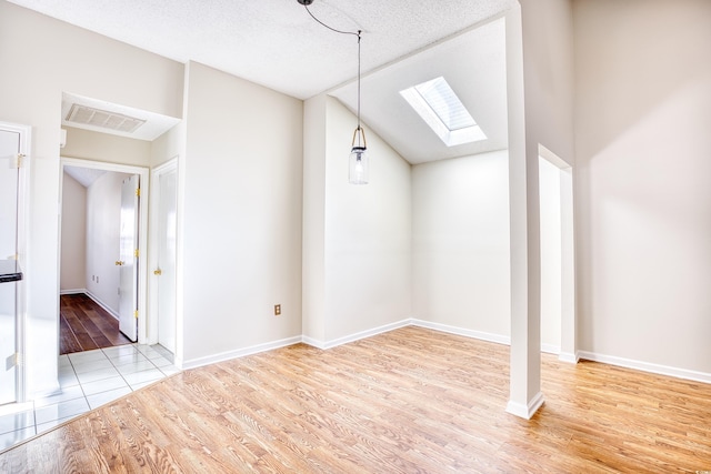 bonus room featuring lofted ceiling with skylight, a textured ceiling, and light hardwood / wood-style flooring