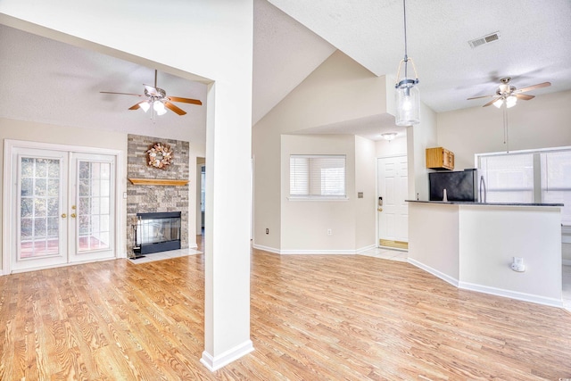 unfurnished living room featuring lofted ceiling, a textured ceiling, light hardwood / wood-style floors, and a fireplace