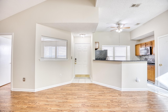 kitchen with decorative backsplash, ceiling fan, refrigerator, and light hardwood / wood-style flooring