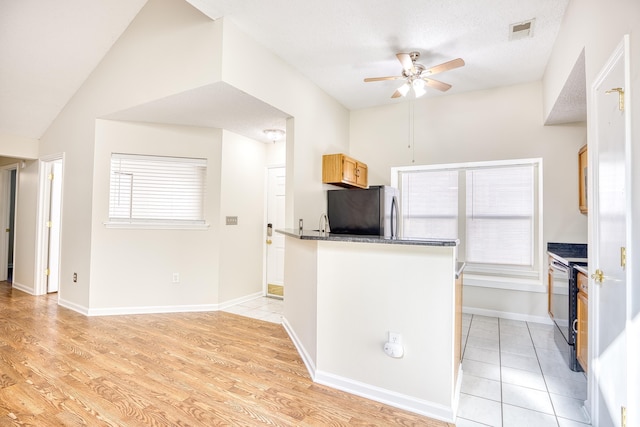 kitchen featuring light brown cabinetry, electric range, stainless steel refrigerator, ceiling fan, and light hardwood / wood-style floors