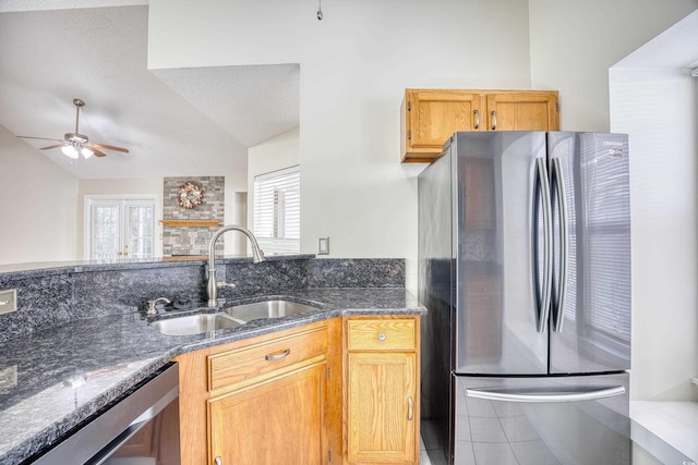 kitchen with dark stone countertops, sink, stainless steel appliances, and lofted ceiling