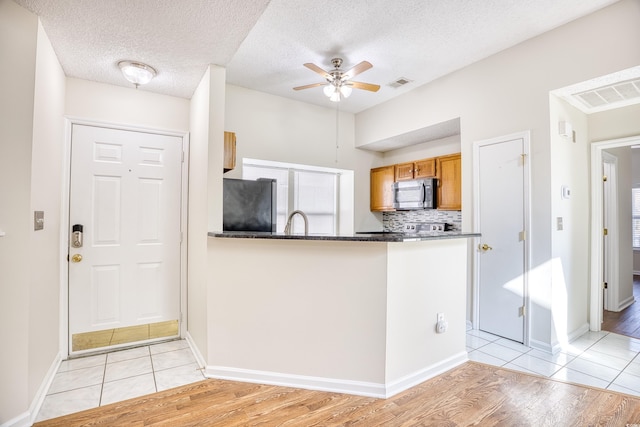 kitchen featuring sink, ceiling fan, backsplash, fridge, and light wood-type flooring