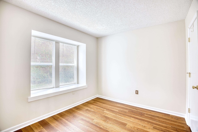 spare room featuring a textured ceiling and light wood-type flooring