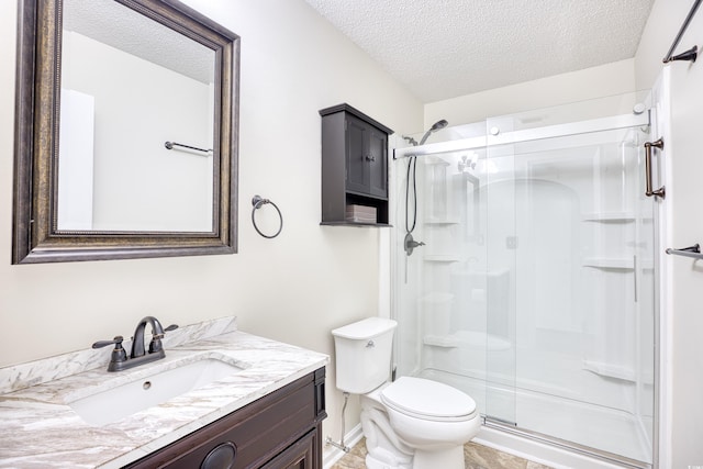 bathroom with vanity, toilet, a textured ceiling, and a shower with shower door