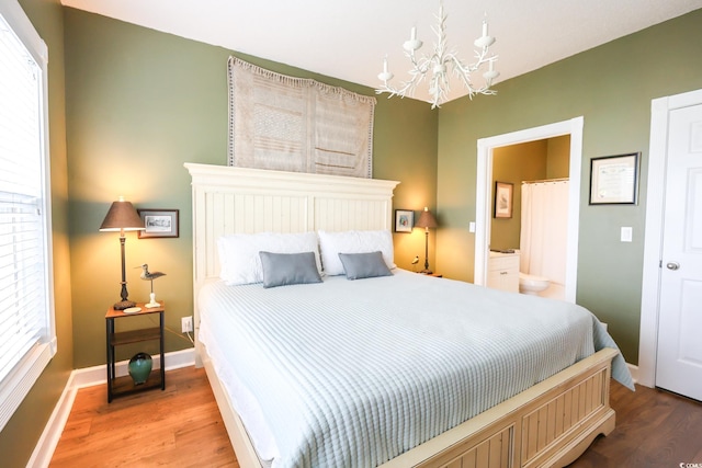 bedroom with hardwood / wood-style floors, ensuite bath, and a chandelier