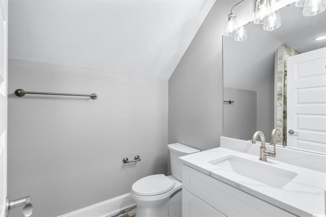 bathroom featuring vanity, toilet, and vaulted ceiling