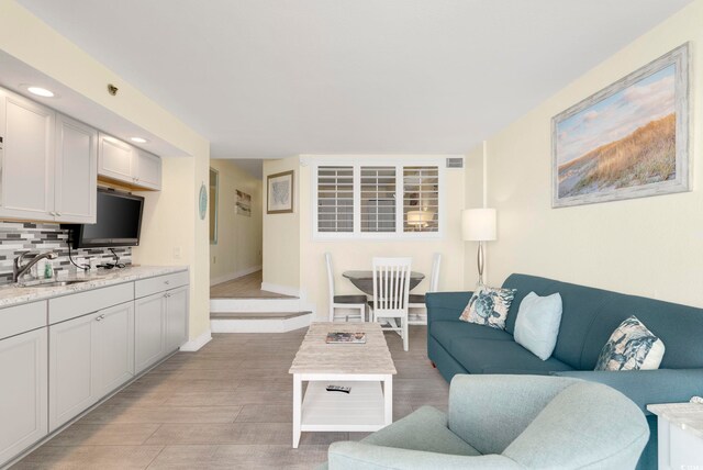 living room featuring sink and light hardwood / wood-style flooring