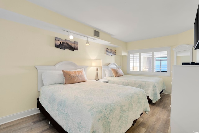 bedroom featuring hardwood / wood-style flooring and track lighting