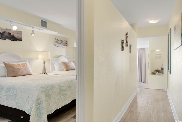 bedroom with track lighting and light hardwood / wood-style flooring