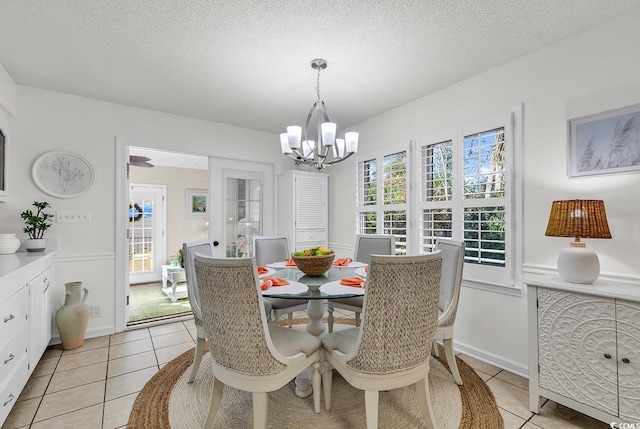 tiled dining space featuring a chandelier and a textured ceiling