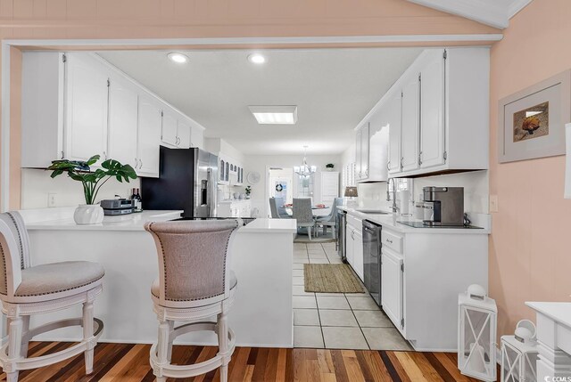 kitchen featuring stainless steel appliances, sink, light tile patterned floors, white cabinetry, and hanging light fixtures