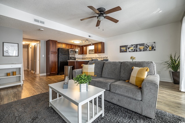 living room featuring ceiling fan, dark hardwood / wood-style floors, and a textured ceiling