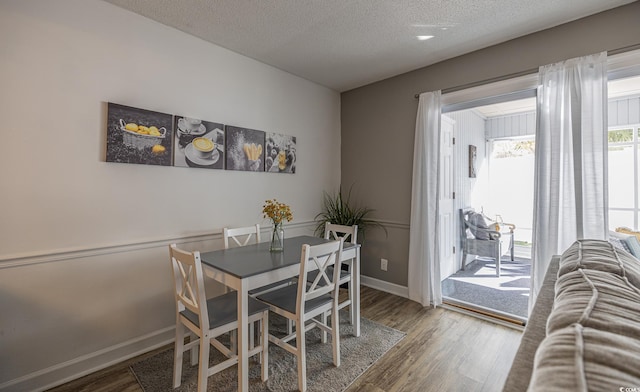 dining space with hardwood / wood-style flooring and a textured ceiling