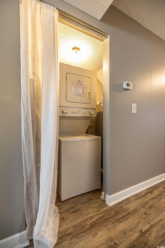 laundry room with hardwood / wood-style floors, stacked washing maching and dryer, and a textured ceiling