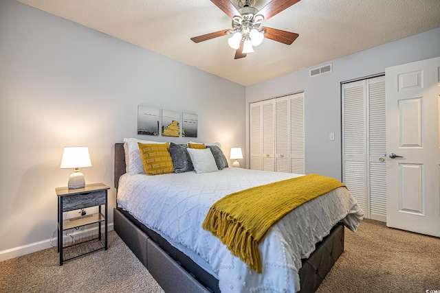 bedroom featuring carpet, a textured ceiling, two closets, and ceiling fan