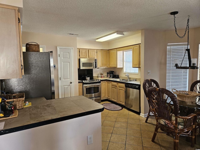 kitchen featuring kitchen peninsula, light brown cabinetry, stainless steel appliances, and sink