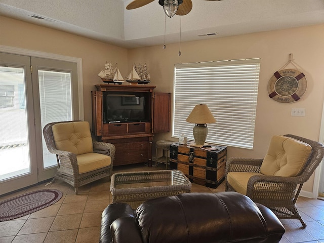 tiled living room featuring ceiling fan and a textured ceiling