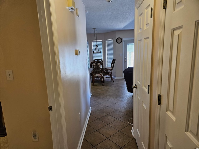 corridor with a textured ceiling and tile patterned floors