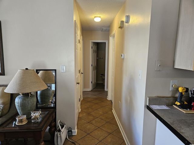 hallway with tile patterned floors and a textured ceiling