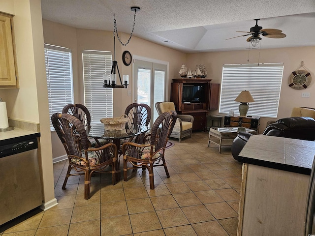 tiled dining space with ceiling fan with notable chandelier, a raised ceiling, and a textured ceiling