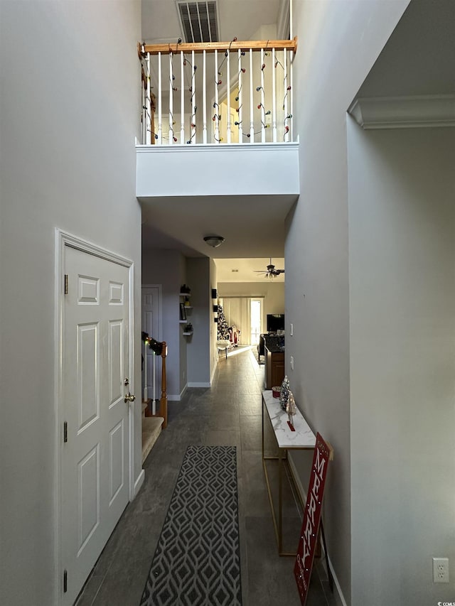 hallway featuring a towering ceiling and ornamental molding