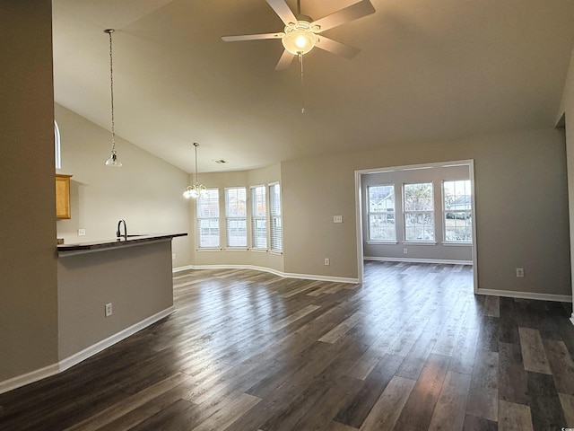 unfurnished living room with a wealth of natural light, sink, ceiling fan with notable chandelier, and dark hardwood / wood-style floors