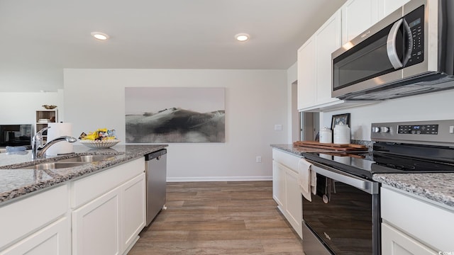 kitchen featuring sink, dark wood-type flooring, stainless steel appliances, light stone countertops, and white cabinets