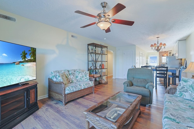 living room with hardwood / wood-style floors, ceiling fan with notable chandelier, and a textured ceiling