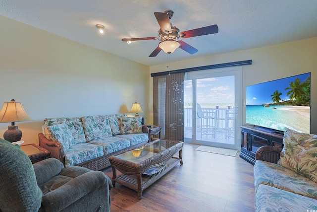 living room featuring ceiling fan, wood-type flooring, and a textured ceiling