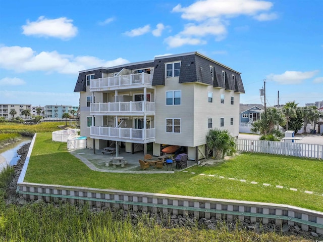 rear view of house featuring a yard, a balcony, and a patio