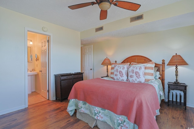 bedroom with ceiling fan, dark wood-type flooring, and connected bathroom