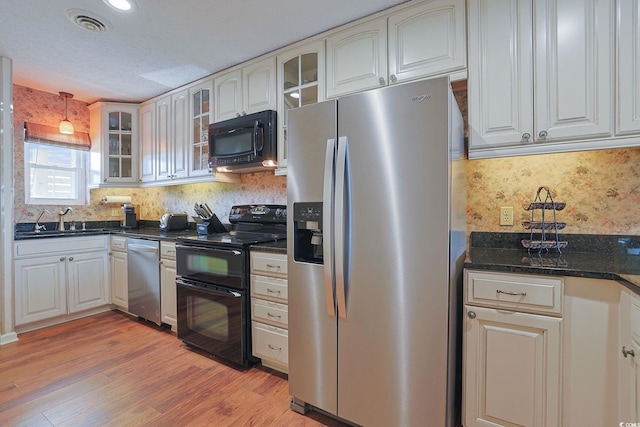 kitchen with sink, black appliances, white cabinets, light hardwood / wood-style floors, and hanging light fixtures