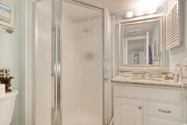 bathroom featuring vanity, toilet, and a shower with door