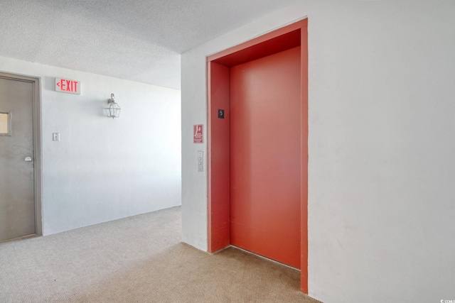 hall with light colored carpet, a textured ceiling, and elevator