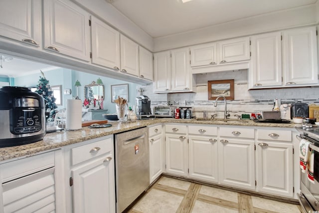 kitchen featuring light stone counters, stainless steel dishwasher, sink, white cabinets, and range