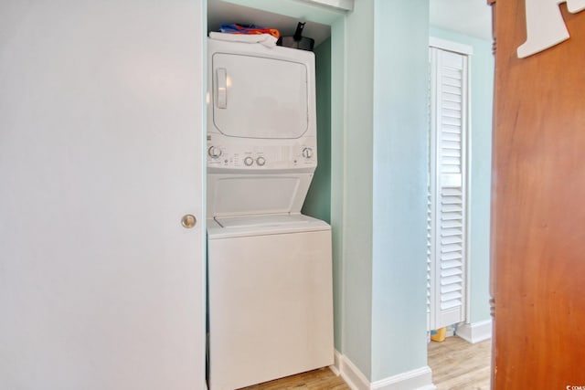 laundry area with stacked washer and clothes dryer and light wood-type flooring