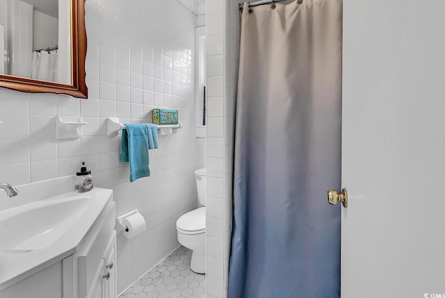 bathroom with tile patterned flooring, vanity, tile walls, and toilet