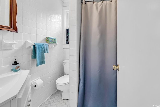 bathroom with tile patterned floors, vanity, toilet, and tile walls