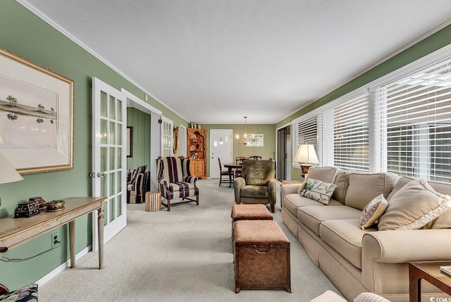 living room with crown molding, a chandelier, french doors, and light colored carpet