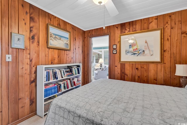 carpeted bedroom featuring ceiling fan, ornamental molding, and wooden walls