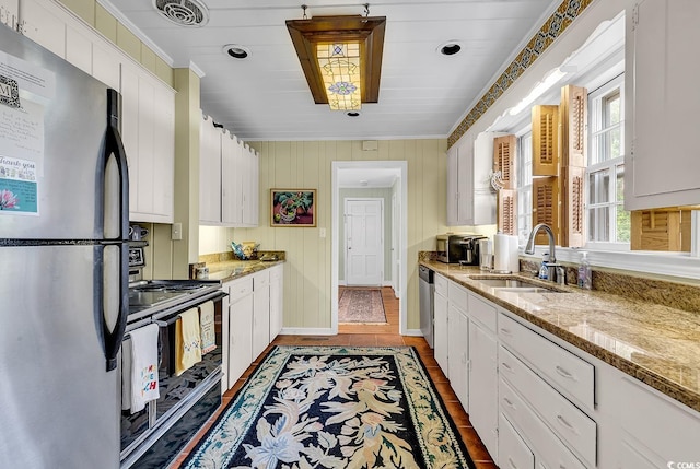 kitchen with light stone countertops, white cabinetry, sink, and stainless steel appliances