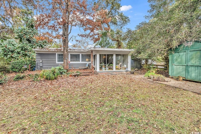 back of house with a sunroom and a shed