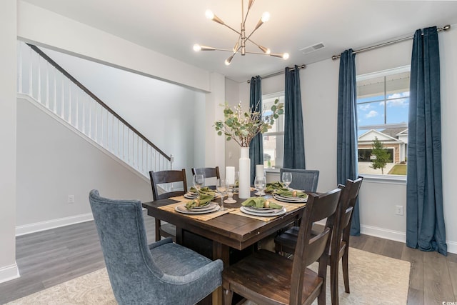 dining space featuring wood-type flooring and an inviting chandelier