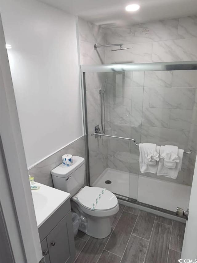 bathroom with walk in shower, vanity, and toilet